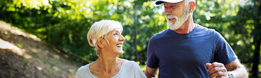 Older man and woman out for a walk on a trail outdoors Older man and woman out for a walk on a trail outdoors